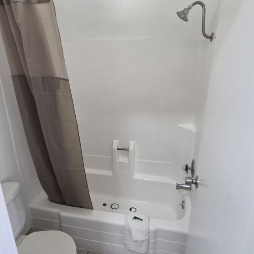 A small bathroom featuring a bathtub with a shower, a curtain, and a toilet, all with a neutral color scheme.